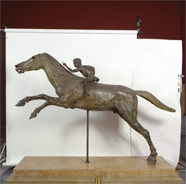 The small jockey held reigns in his left hand while the bronze horse is galloping with tremendous speed