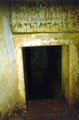 Nine burial chambers with doors are arranged around a large central space and the names of the deceased are written above each door